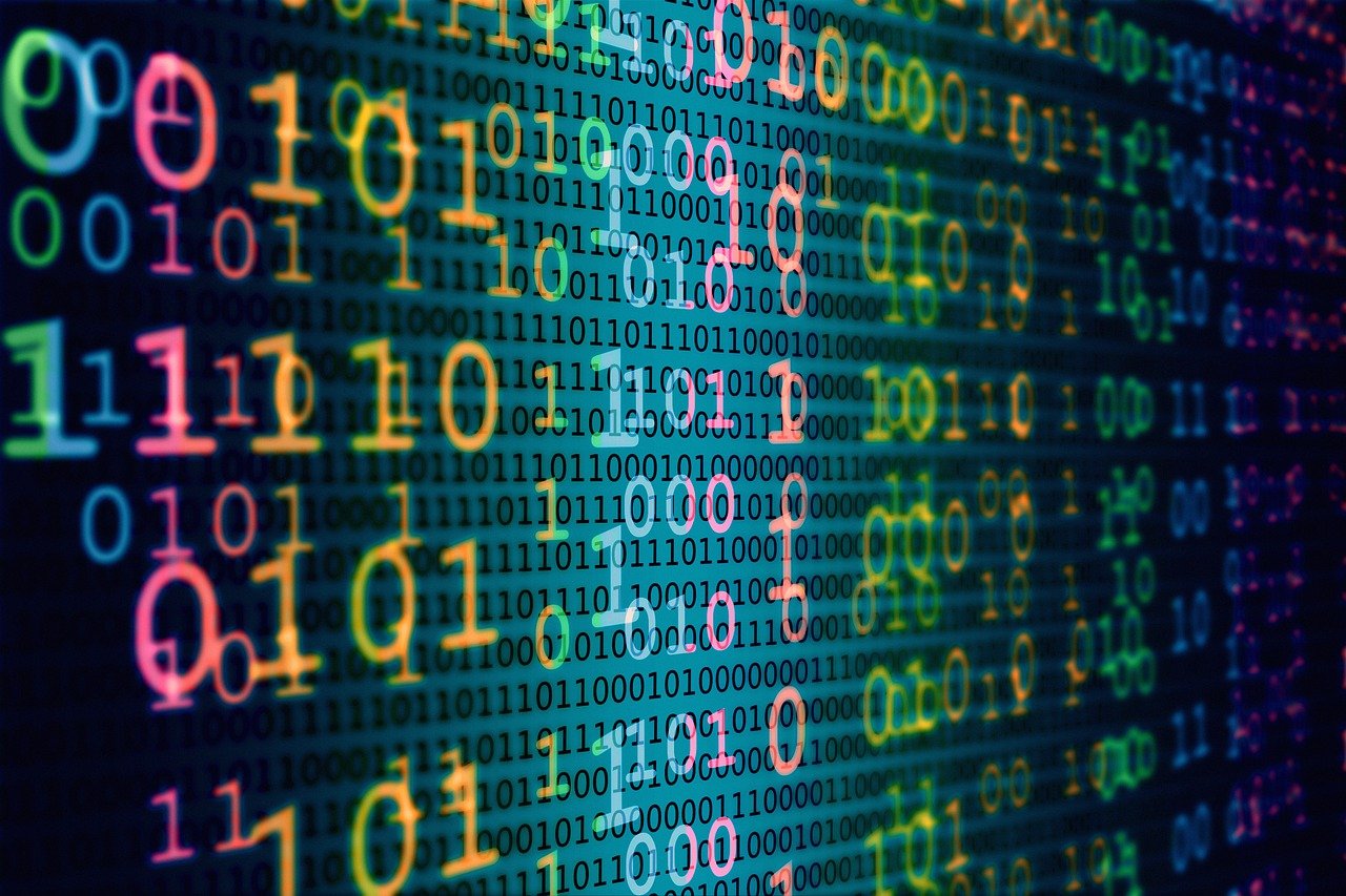 A vibrant digital art image showing streams of colorful binary code (ones and zeros) flowing across a dark background. The numbers appear in bright neon colors including green, pink, orange, yellow, and blue, creating a dynamic cyberpunk aesthetic that suggests data flow, computer programming, or digital technology concepts.